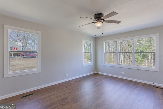 spare room with a healthy amount of sunlight, ceiling fan, and dark hardwood / wood-style flooring