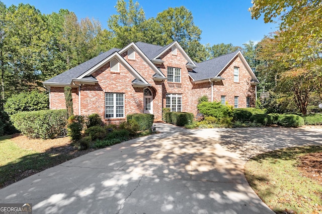 view of front of house featuring brick siding and roof with shingles