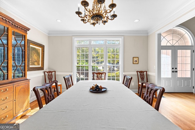 dining area with a notable chandelier, wood finished floors, and crown molding