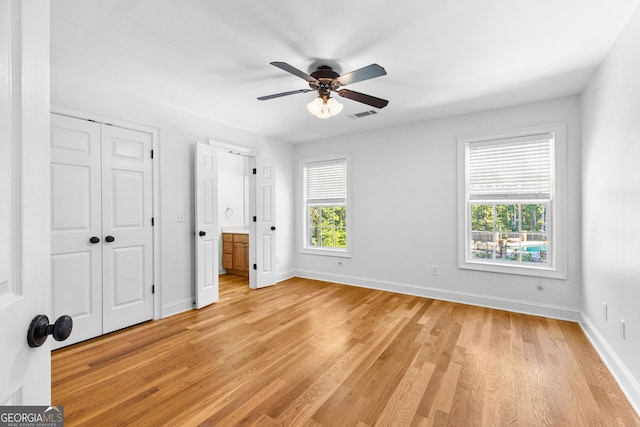 unfurnished bedroom featuring light wood-type flooring, visible vents, baseboards, and ensuite bath