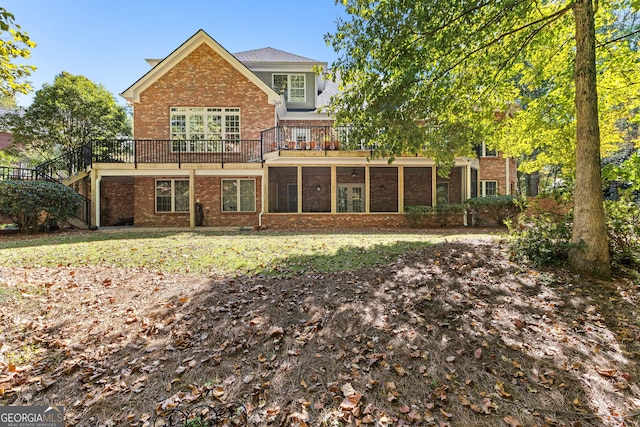 back of property with brick siding, a yard, and a sunroom