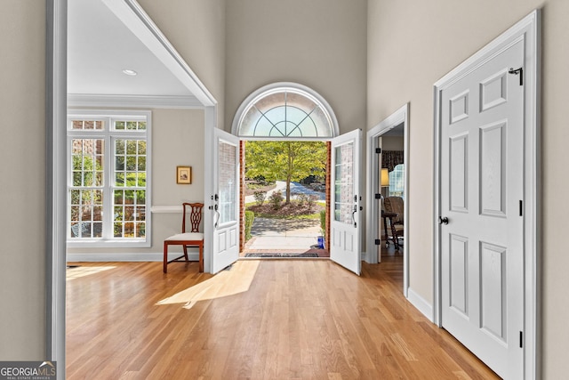 entryway featuring a wealth of natural light, crown molding, light wood-type flooring, and baseboards