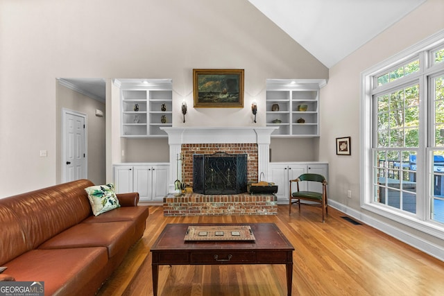 living room with visible vents, crown molding, baseboards, a fireplace, and wood finished floors