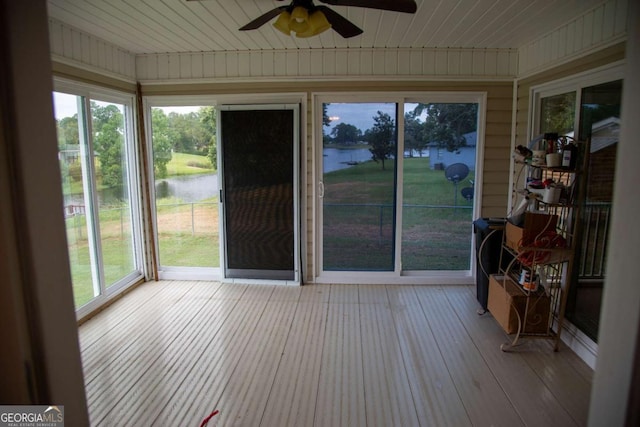 unfurnished sunroom with ceiling fan and a water view