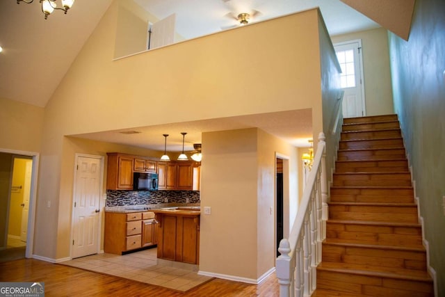 kitchen with light hardwood / wood-style floors, high vaulted ceiling, pendant lighting, and tasteful backsplash