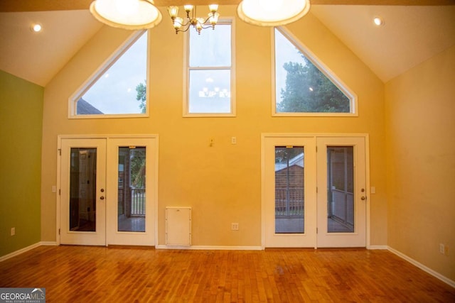 interior space with a notable chandelier, french doors, high vaulted ceiling, and wood-type flooring