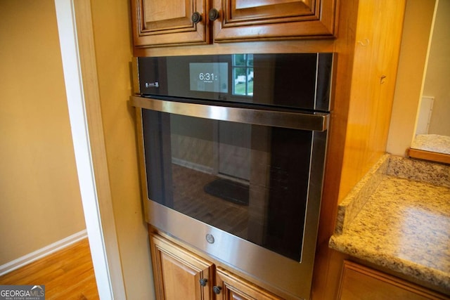 room details with light stone counters, light hardwood / wood-style floors, and double oven