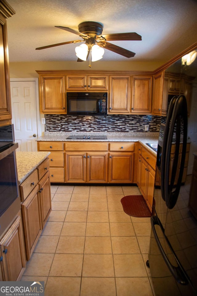 kitchen featuring black appliances, light stone countertops, tasteful backsplash, ceiling fan, and light tile patterned flooring