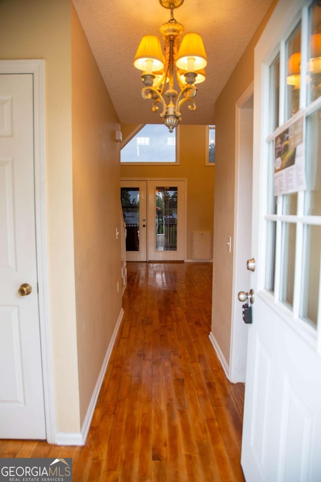 hallway with hardwood / wood-style flooring, an inviting chandelier, and a textured ceiling