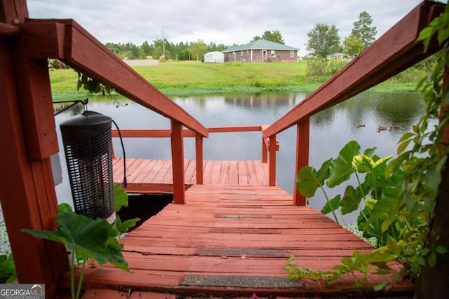 view of dock featuring a lawn and a water view