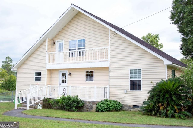 back of property with a balcony and a yard