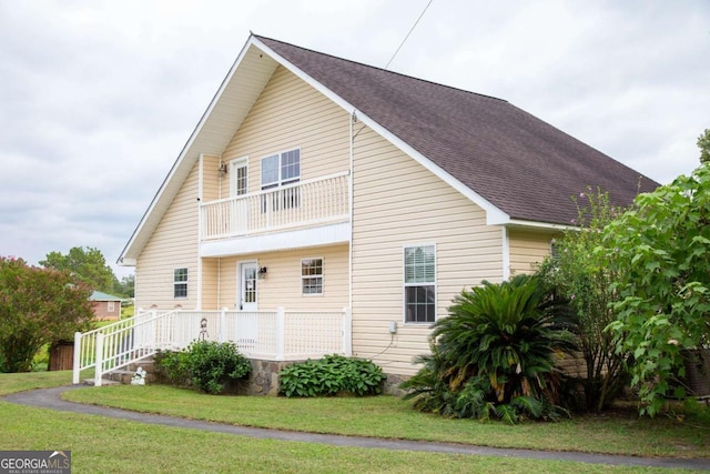 view of property exterior featuring a balcony and a yard