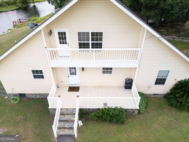 back of house featuring a deck, a balcony, and a lawn