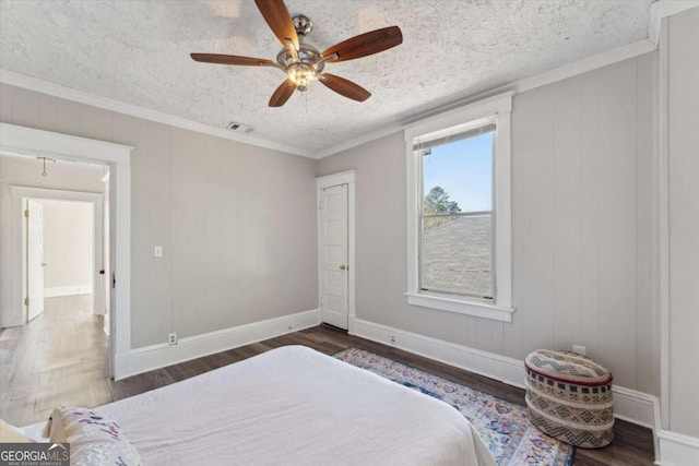 bedroom with ceiling fan, a textured ceiling, dark hardwood / wood-style flooring, and ornamental molding