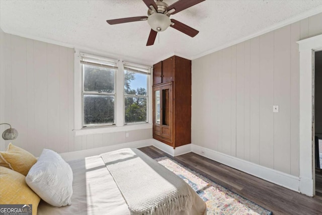 bedroom featuring ceiling fan, a textured ceiling, dark hardwood / wood-style floors, and crown molding