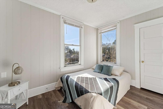 bedroom featuring wooden walls, a textured ceiling, dark hardwood / wood-style floors, and ornamental molding