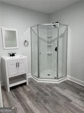 bathroom featuring wood-type flooring, an enclosed shower, and vanity