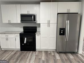 kitchen with light stone countertops, white cabinetry, appliances with stainless steel finishes, and light hardwood / wood-style flooring