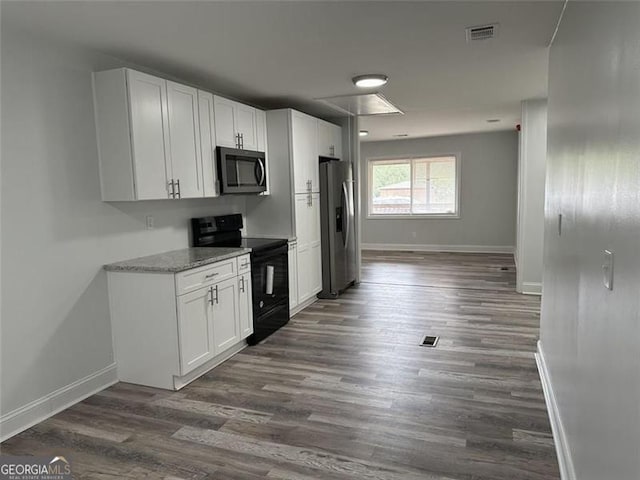 kitchen with light stone countertops, white cabinets, appliances with stainless steel finishes, and dark hardwood / wood-style floors