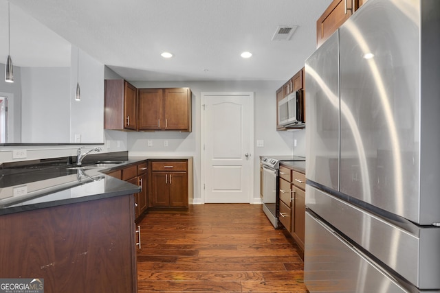 kitchen featuring sink, stainless steel appliances, dark wood-type flooring, and decorative light fixtures