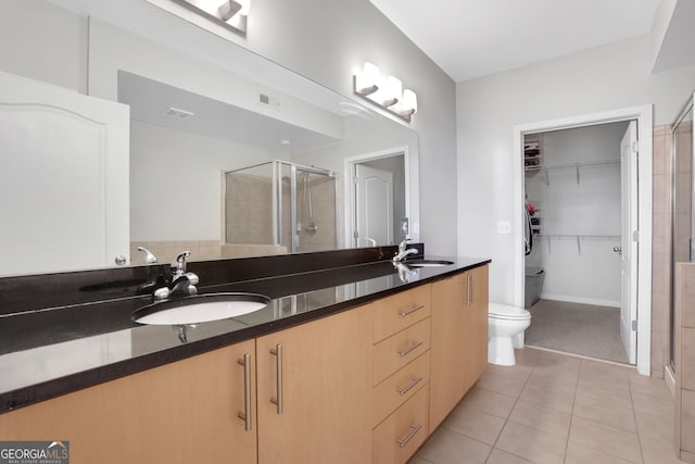 bathroom featuring toilet, tile patterned flooring, walk in shower, and vanity