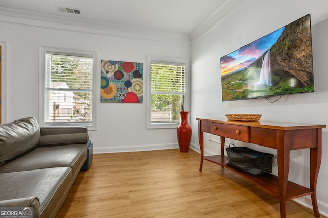 living area featuring light wood-style floors, ornamental molding, baseboards, and visible vents