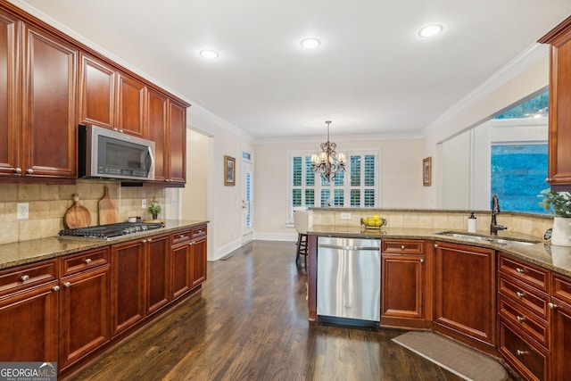 kitchen featuring light stone countertops, appliances with stainless steel finishes, hanging light fixtures, sink, and dark hardwood / wood-style floors