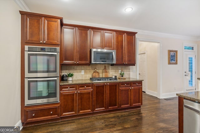 kitchen with dark hardwood / wood-style flooring, stainless steel appliances, tasteful backsplash, stone countertops, and crown molding