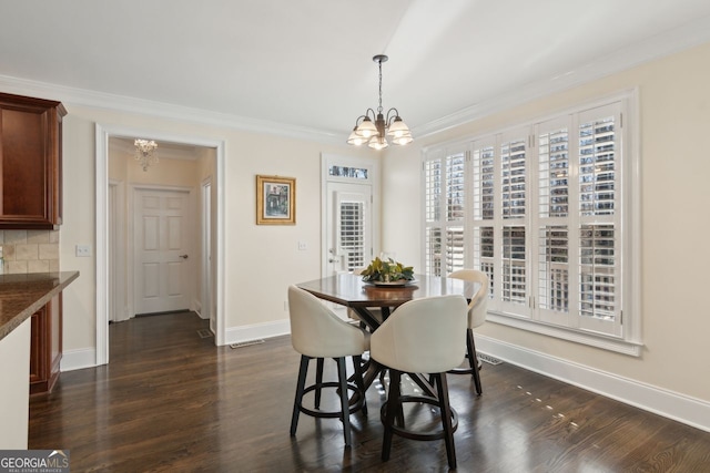 dining room featuring dark wood-type flooring, crown molding, and a chandelier