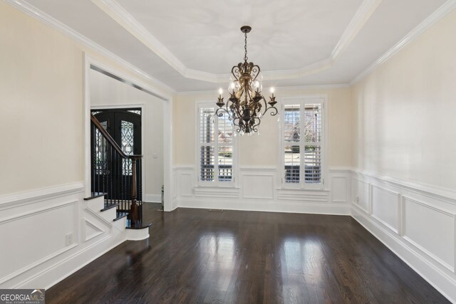 unfurnished dining area with a notable chandelier, a raised ceiling, crown molding, and dark hardwood / wood-style floors