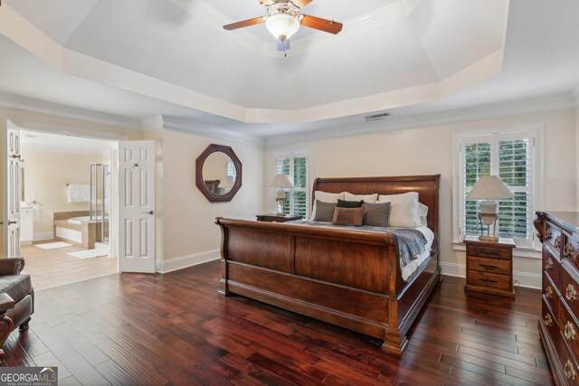 bedroom featuring ceiling fan, a raised ceiling, dark hardwood / wood-style floors, ornamental molding, and connected bathroom