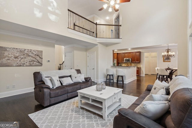 living room with dark wood-type flooring, ceiling fan with notable chandelier, and a high ceiling