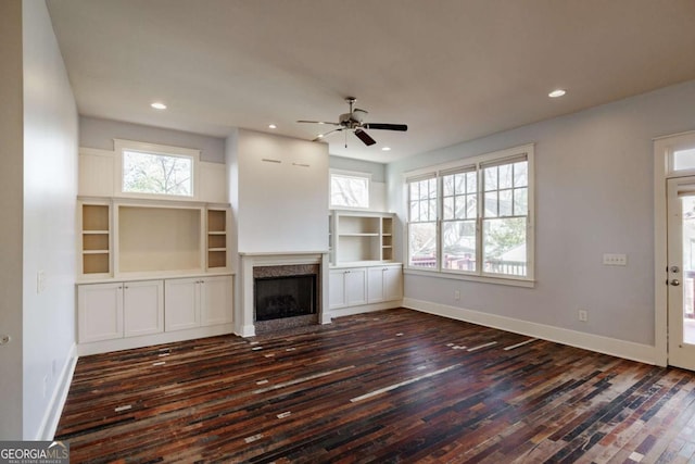 unfurnished living room featuring dark wood-type flooring and ceiling fan