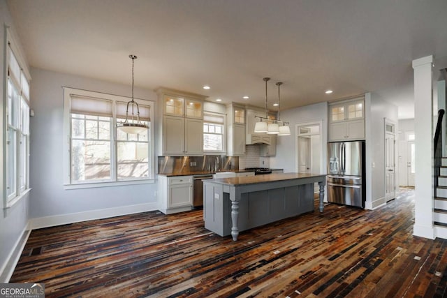 kitchen with a kitchen island, a healthy amount of sunlight, decorative backsplash, and appliances with stainless steel finishes