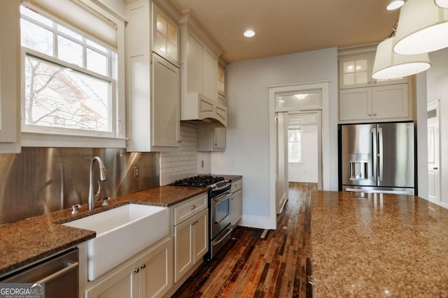 kitchen with hanging light fixtures, sink, tasteful backsplash, light stone counters, and stainless steel appliances