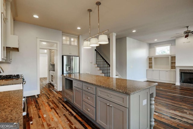 kitchen with a center island, stone counters, stainless steel fridge with ice dispenser, gray cabinetry, and decorative light fixtures