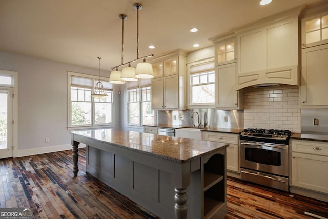 kitchen featuring appliances with stainless steel finishes, a center island, tasteful backsplash, dark stone countertops, and sink