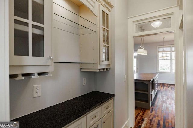 kitchen featuring decorative light fixtures, dark wood-type flooring, and dark stone countertops