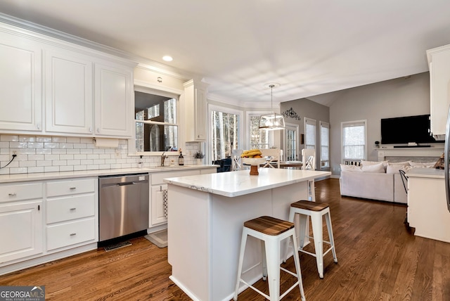 kitchen with a kitchen bar, a center island, stainless steel dishwasher, pendant lighting, and white cabinets