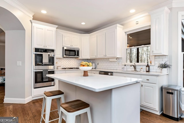 kitchen with a kitchen island, dark hardwood / wood-style floors, sink, white cabinets, and stainless steel appliances