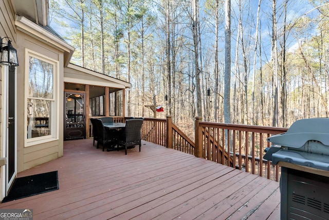 wooden deck featuring a sunroom and a grill