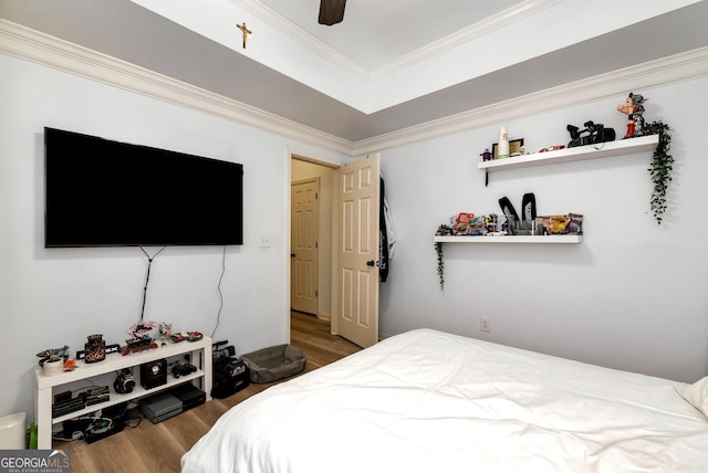 bedroom with hardwood / wood-style floors, ornamental molding, a raised ceiling, and ceiling fan