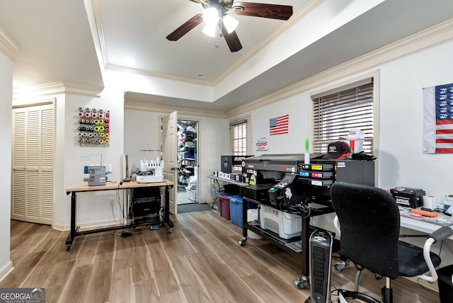 office area featuring ceiling fan, ornamental molding, a raised ceiling, and light hardwood / wood-style floors