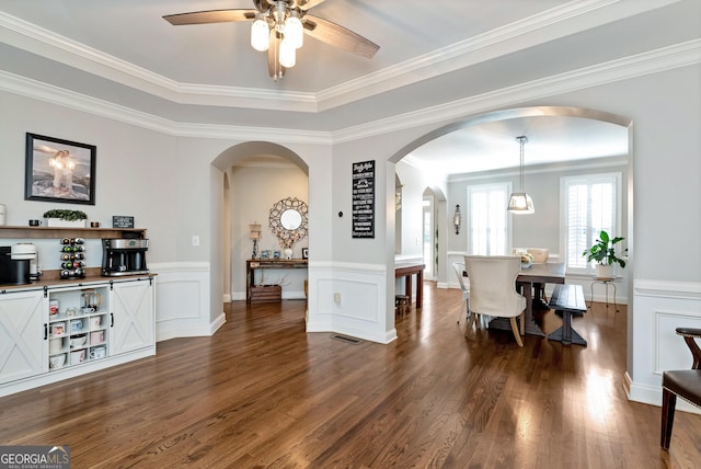 interior space with dark wood-type flooring, ornamental molding, and ceiling fan