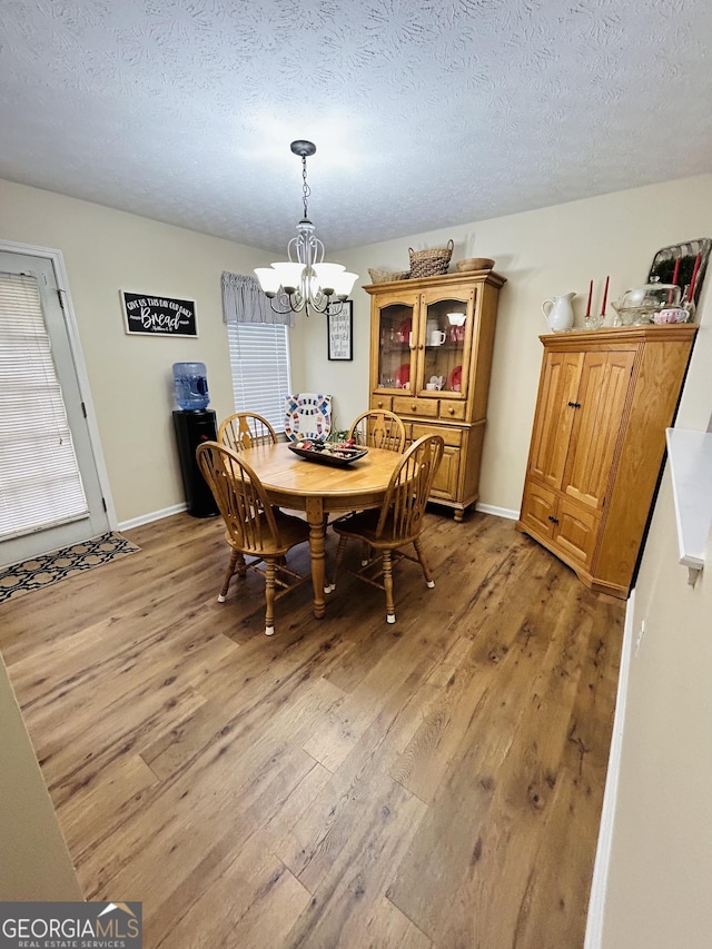 dining space featuring an inviting chandelier, light hardwood / wood-style flooring, and a textured ceiling