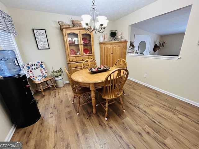 dining room with an inviting chandelier, a textured ceiling, and light hardwood / wood-style floors