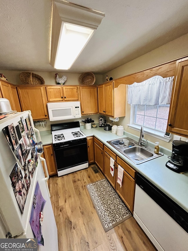 kitchen with light hardwood / wood-style floors, sink, white appliances, and a textured ceiling