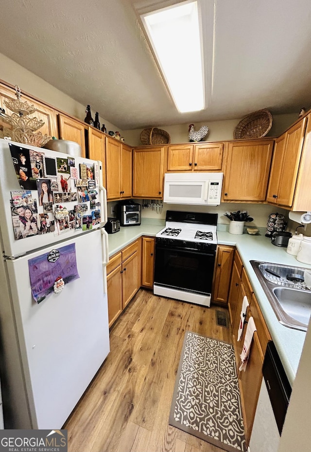 kitchen with sink, white appliances, and light wood-type flooring