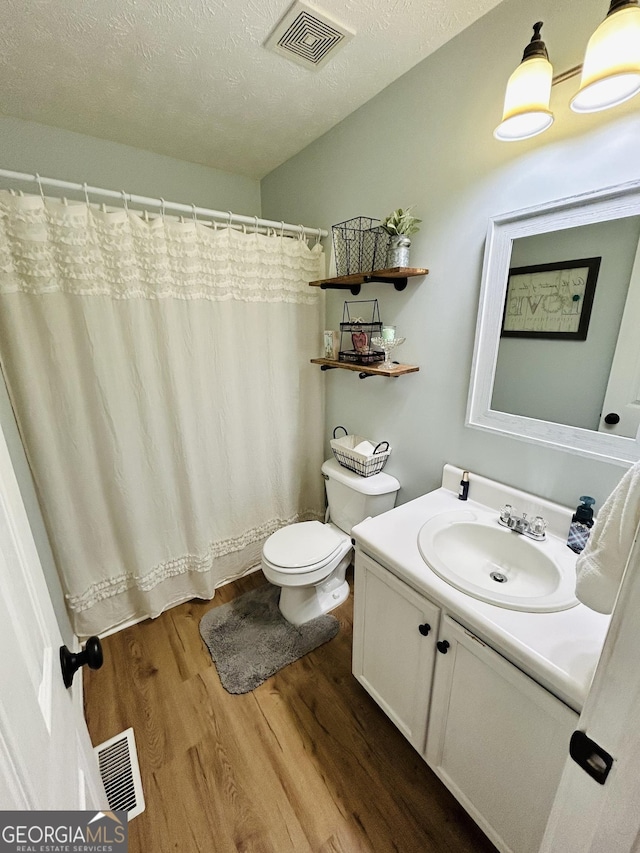 bathroom with vanity, toilet, hardwood / wood-style floors, and a textured ceiling