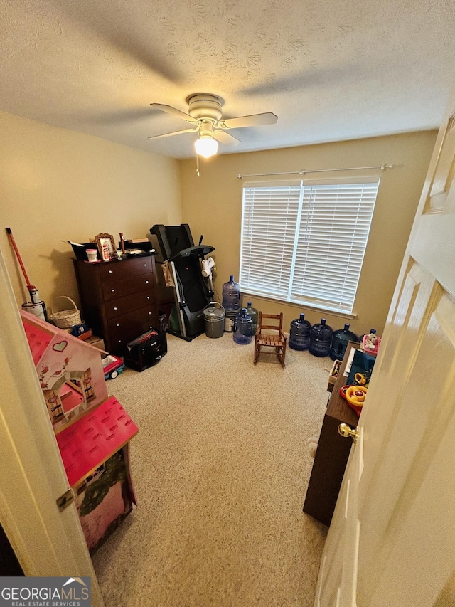 interior space with ceiling fan, a textured ceiling, and carpet flooring